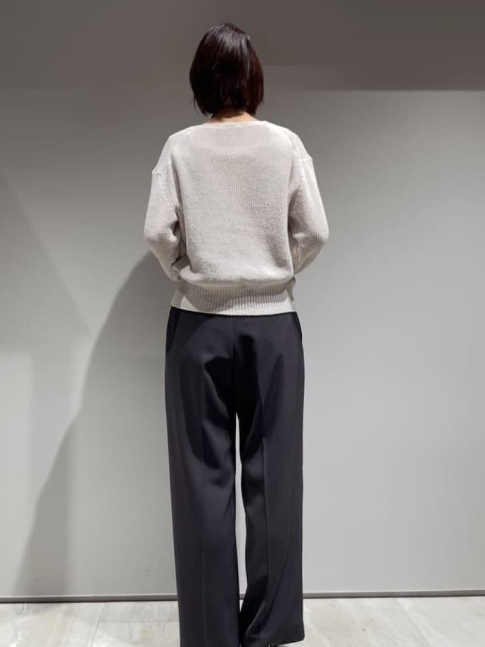 グレー系のその他パンツ、ベージュ系のニット/セーター、ホワイト系のタンクトップを着用したレディースの春コーディネートの6枚目の写真