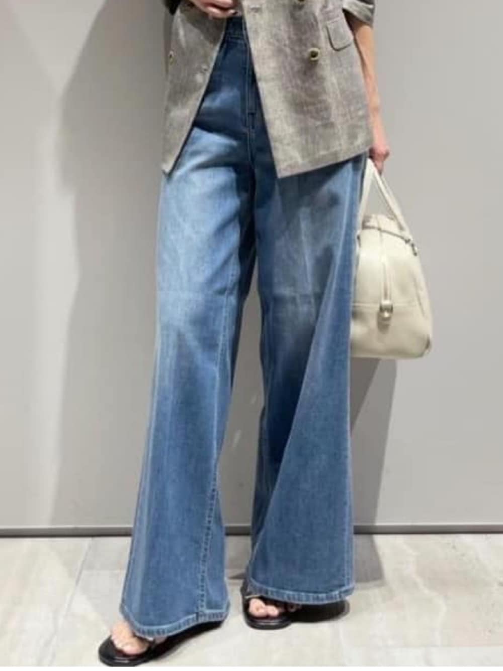 ブルー系のデニムパンツ、ベージュ系のテーラードジャケット、ホワイト系のタンクトップを着用したレディースの春コーディネートの5枚目の写真