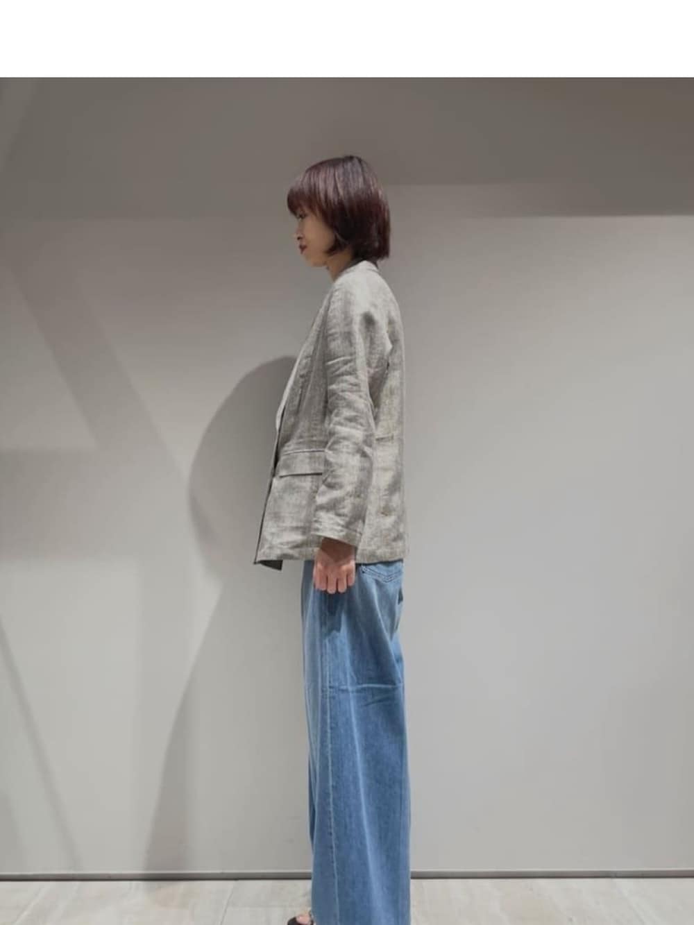 ブルー系のデニムパンツ、ベージュ系のテーラードジャケット、ホワイト系のタンクトップを着用したレディースの春コーディネートの6枚目の写真