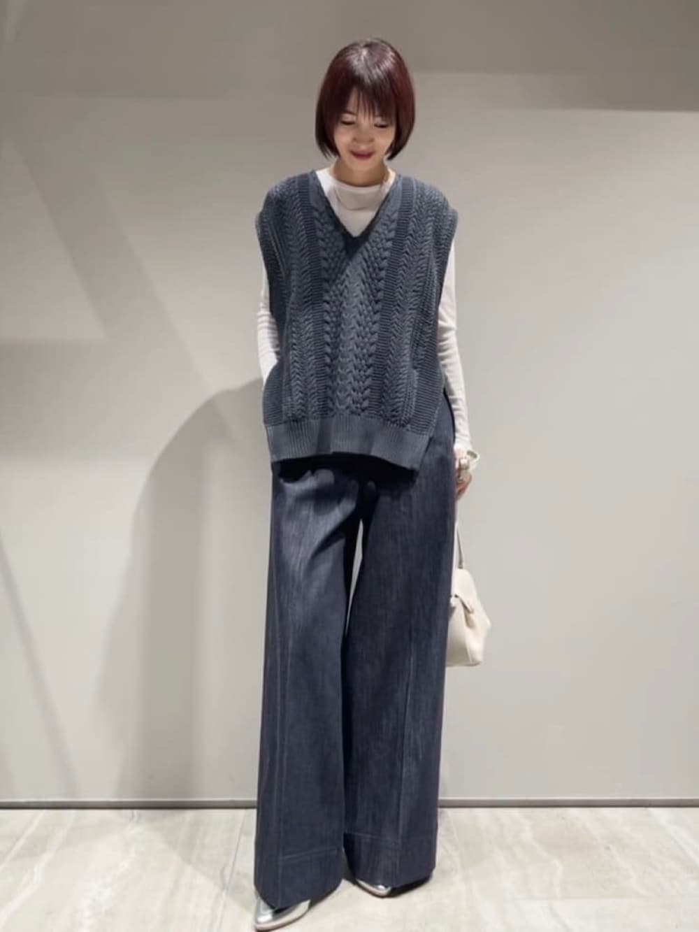 ブルー系のデニムパンツ、ホワイト系のショルダーバッグ、ホワイト系のTシャツ/カットソーを着用したレディースの冬コーディネートの2枚目の写真