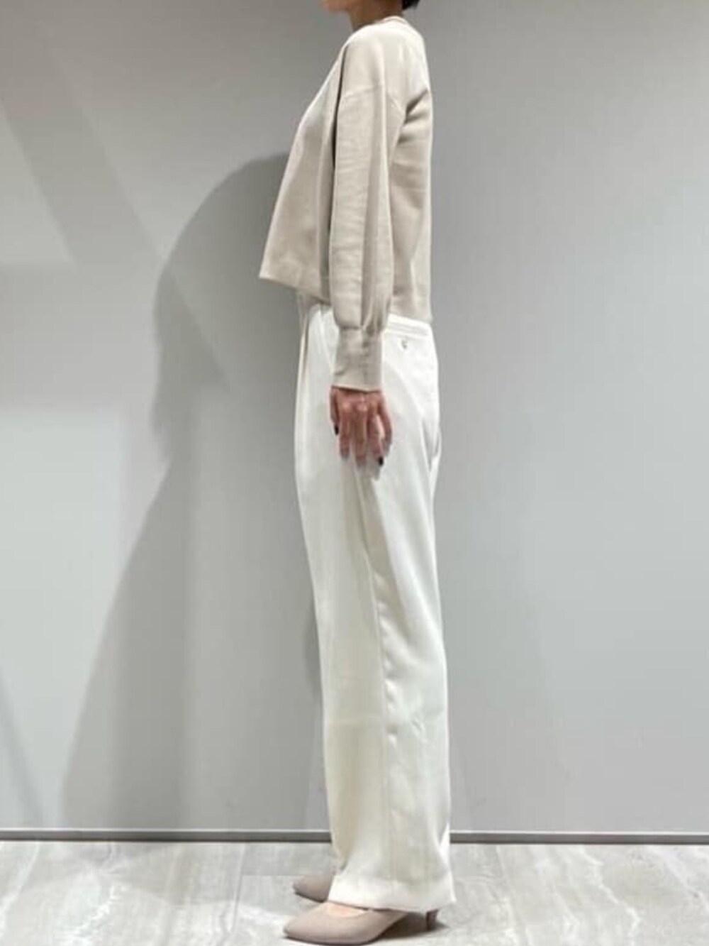 ベージュ系のニット/セーター、ホワイト系のスラックス、ゴールド系のネックレスを着用したレディースの秋コーディネートの5枚目の写真