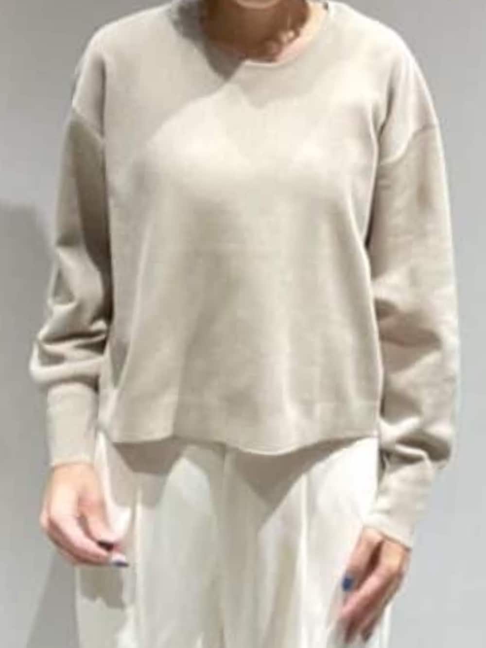 ベージュ系のニット/セーター、ホワイト系のスラックス、ゴールド系のネックレスを着用したレディースの秋コーディネートの3枚目の写真