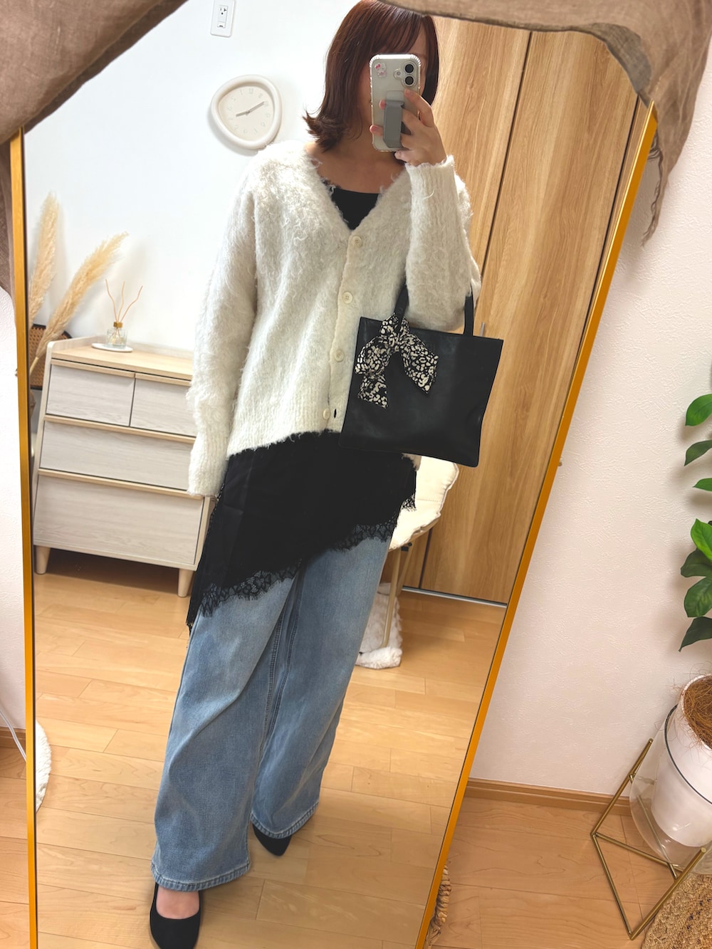 ブルー系のデニムパンツ、ブラック系のキャミソール、ホワイト系のカーディガン/ボレロを着用したレディースの冬コーディネートの2枚目の写真