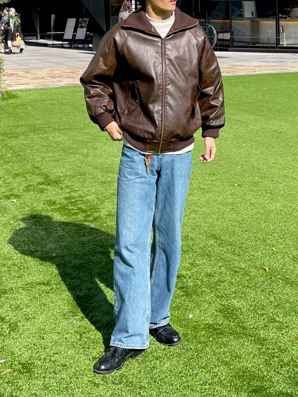 ブラウン系のブルゾン、ブルー系のデニムパンツ、ホワイト系のニット/セーターを着用したメンズの秋コーディネートの2枚目の写真