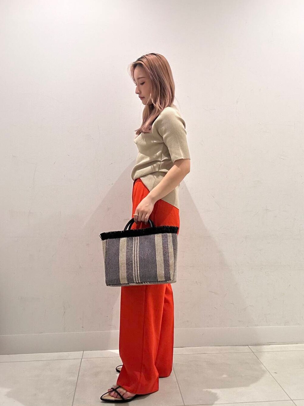 レッド系のその他パンツ、ブラック系のサンダル、ベージュ系のニット/セーターを着用したレディースの春コーディネートの3枚目の写真