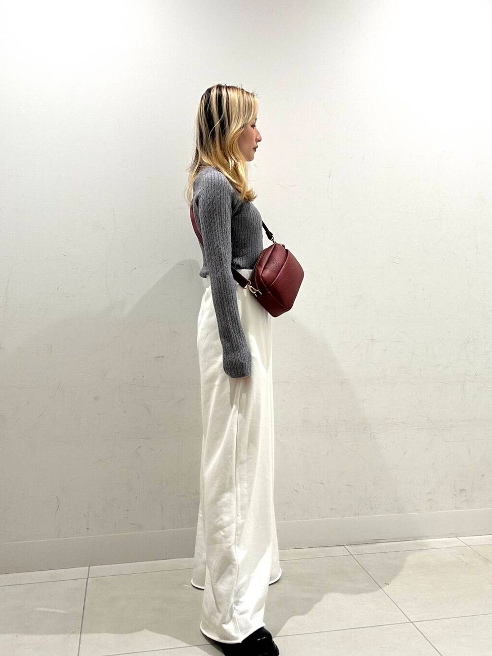 レッド系のショルダーバッグ、ブラック系のダウンジャケット/コート、ブラック系のブーツを着用したレディースの秋コーディネートの2枚目の写真