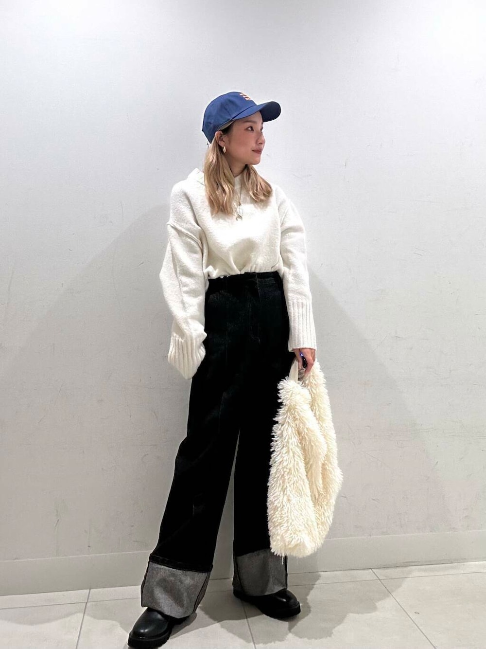 ブラック系のブーツ、ホワイト系のトートバッグ、ブルー系のデニムパンツを着用したレディースの冬コーディネートの3枚目の写真