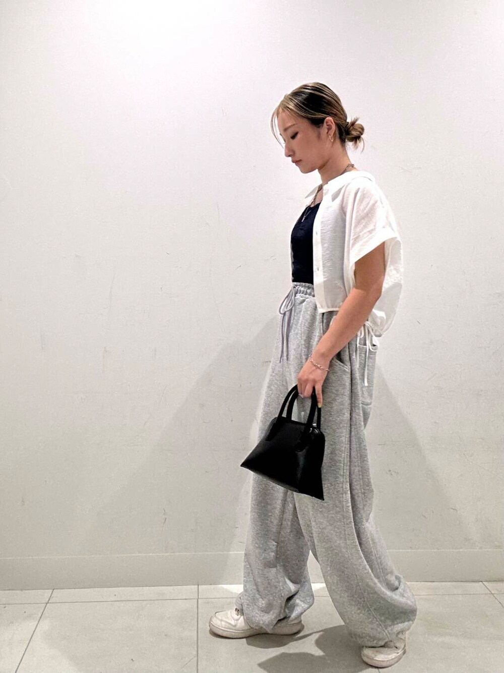 ブラック系のショルダーバッグ、ホワイト系のシャツ/ブラウス、ブルー系のキャミソールを着用したレディースの夏コーディネートの3枚目の写真