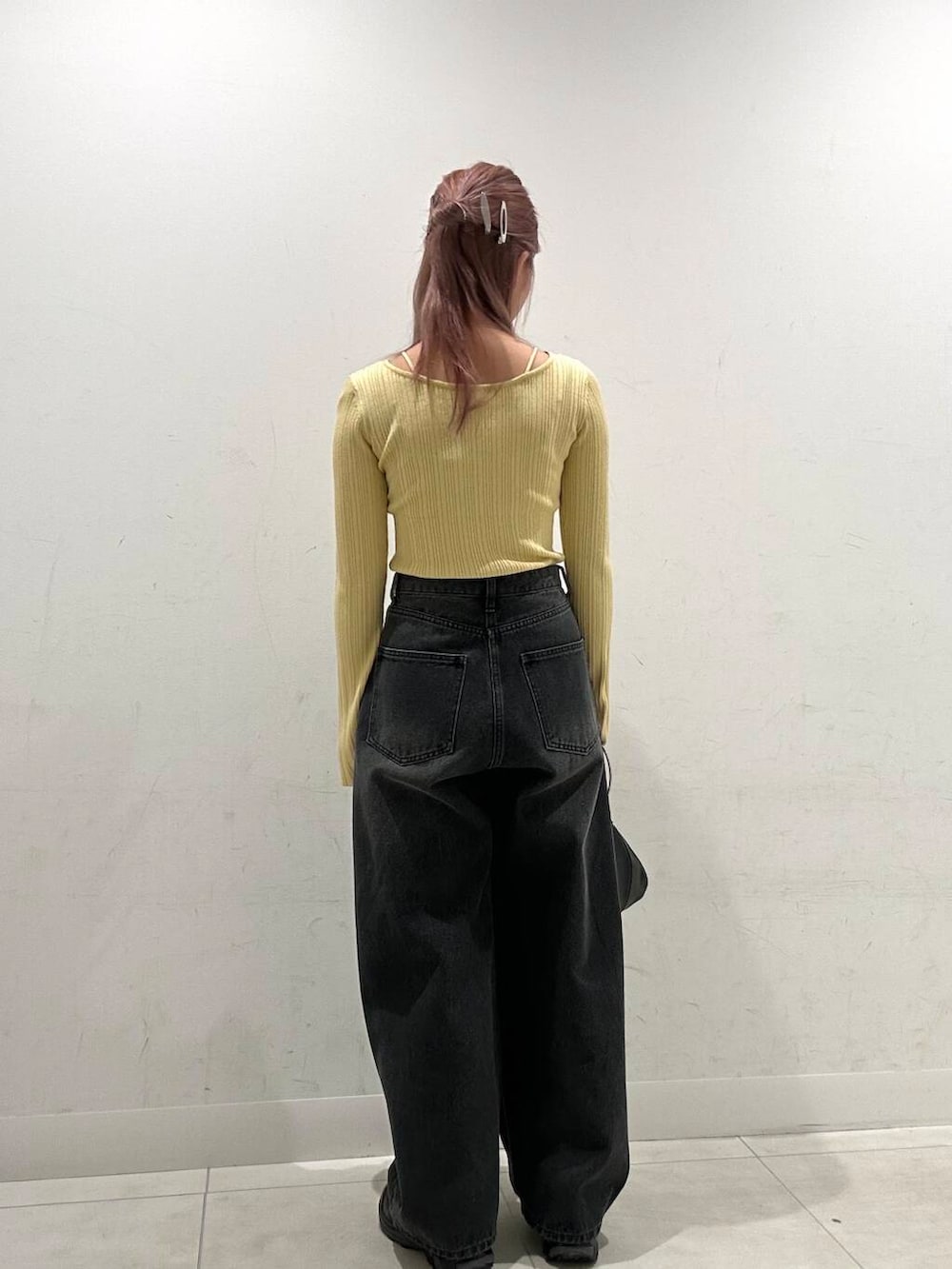 ブラック系のハンドバッグ、ブラック系のスニーカー、イエロー系のニット/セーターを着用したレディースの春コーディネートの3枚目の写真