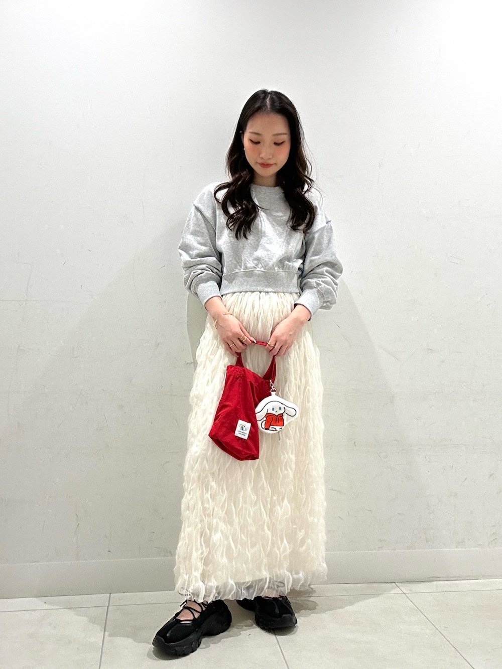 ホワイト系のスカート、レッド系のエコバッグ/サブバッグ、グレー系のスウェットを着用したレディースの春コーディネートの2枚目の写真