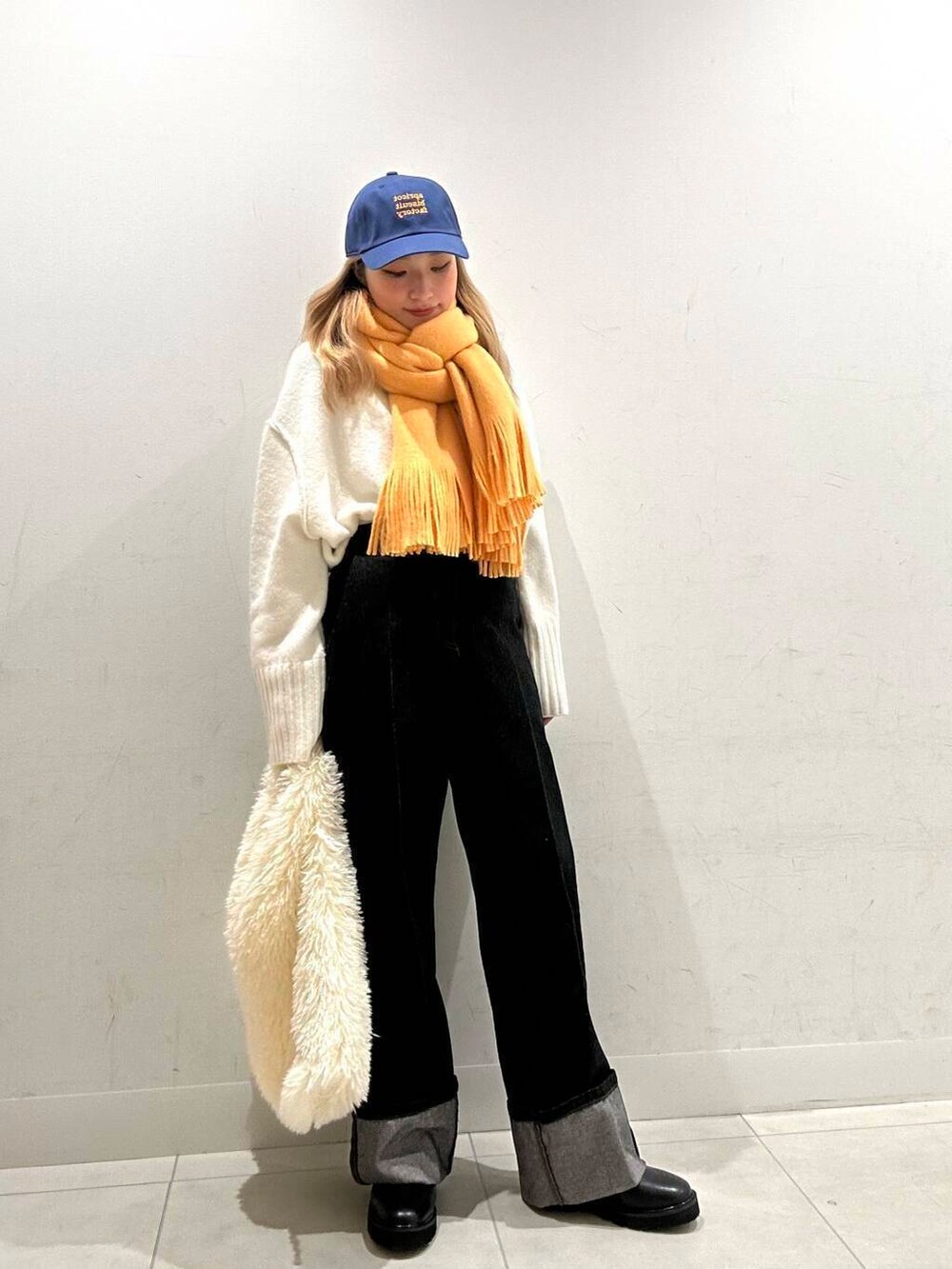 ブラック系のブーツ、ホワイト系のトートバッグ、ブルー系のデニムパンツを着用したレディースの冬コーディネートの2枚目の写真