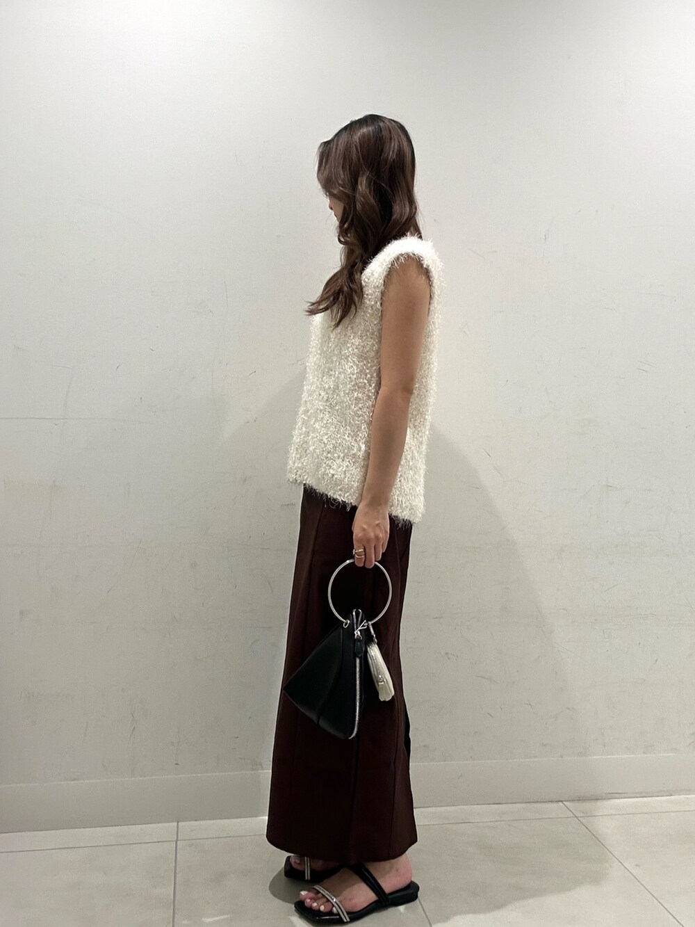 ホワイト系のベスト、ブラウン系のスカート、ブラック系のハンドバッグを着用したレディースの夏コーディネートの3枚目の写真