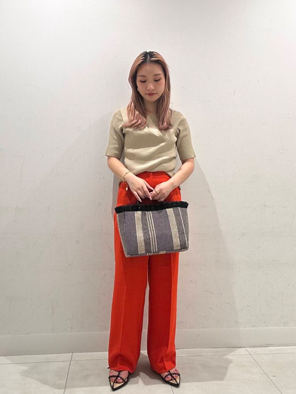 レッド系のその他パンツ、ブラック系のサンダル、ベージュ系のニット/セーターを着用したレディースの春コーディネートの2枚目の写真