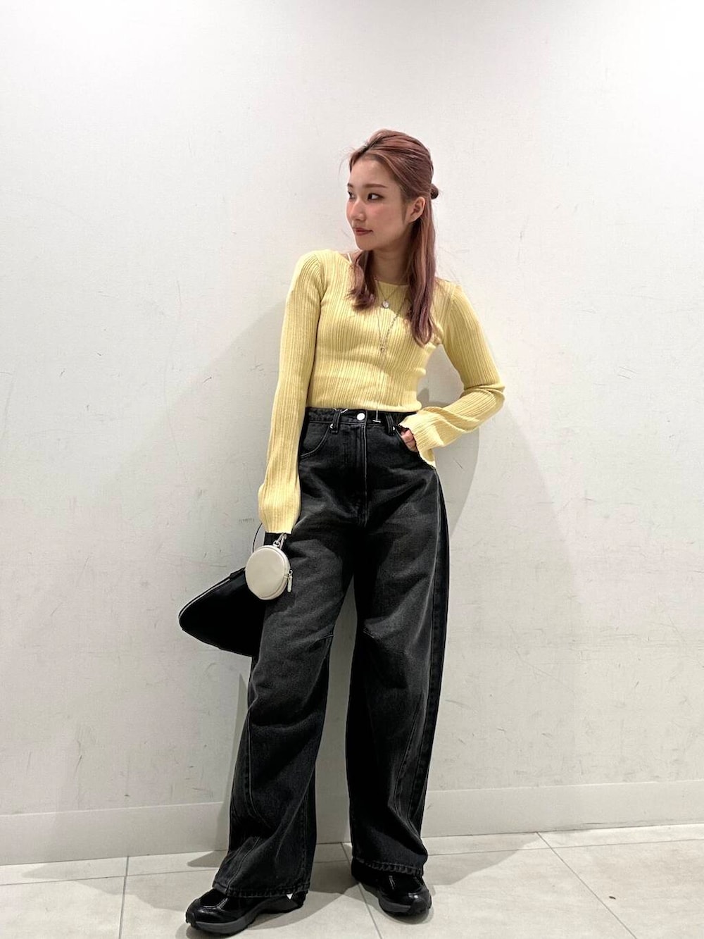 ブラック系のハンドバッグ、ブラック系のスニーカー、イエロー系のニット/セーターを着用したレディースの春コーディネートの2枚目の写真