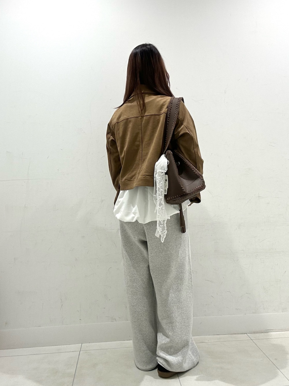 ブラウン系のショルダーバッグ、グレー系のスウェットパンツ、ブラウン系のスニーカーを着用したレディースの秋コーディネートの3枚目の写真