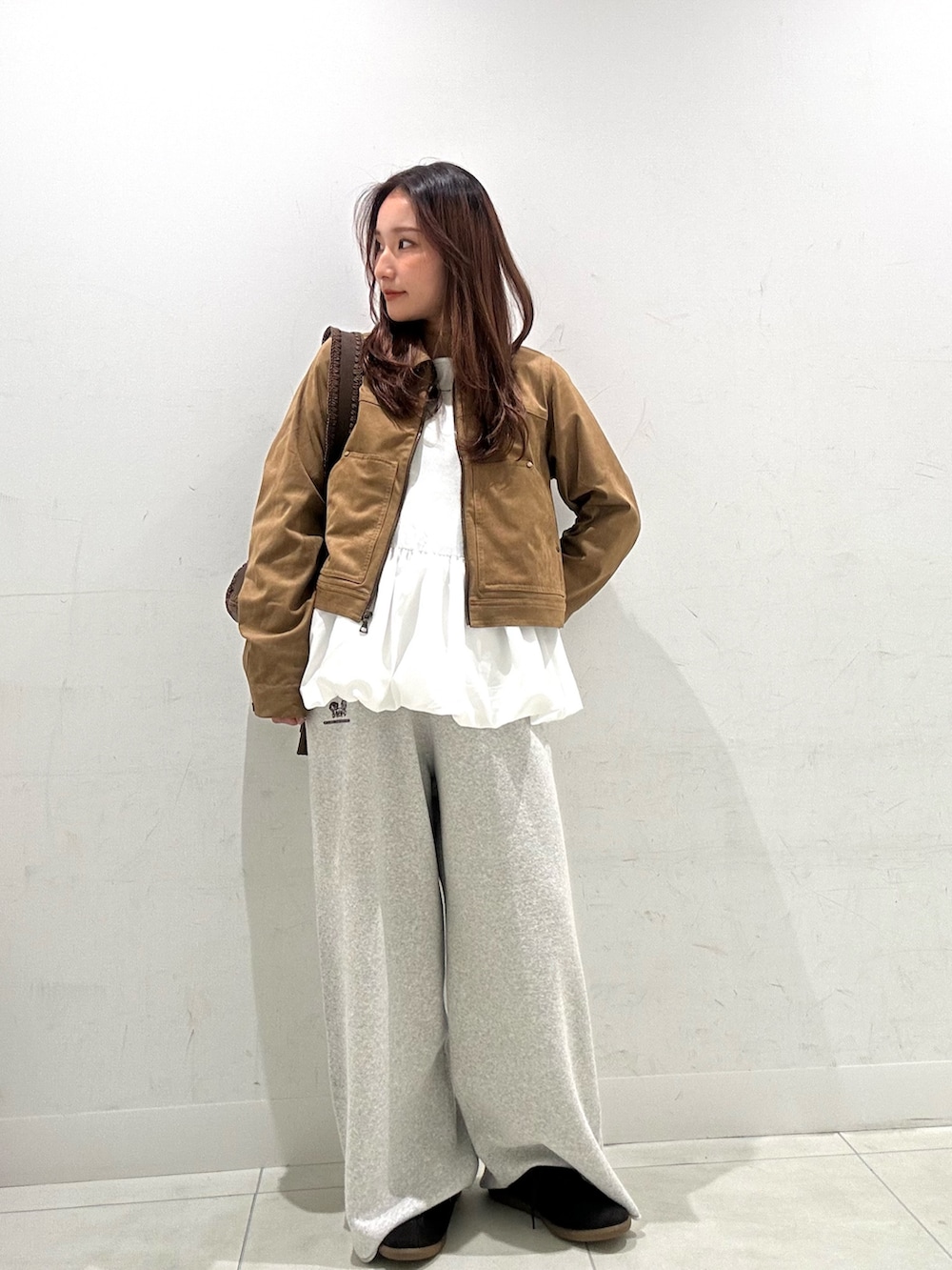 ブラウン系のショルダーバッグ、グレー系のスウェットパンツ、ブラウン系のスニーカーを着用したレディースの秋コーディネートの2枚目の写真