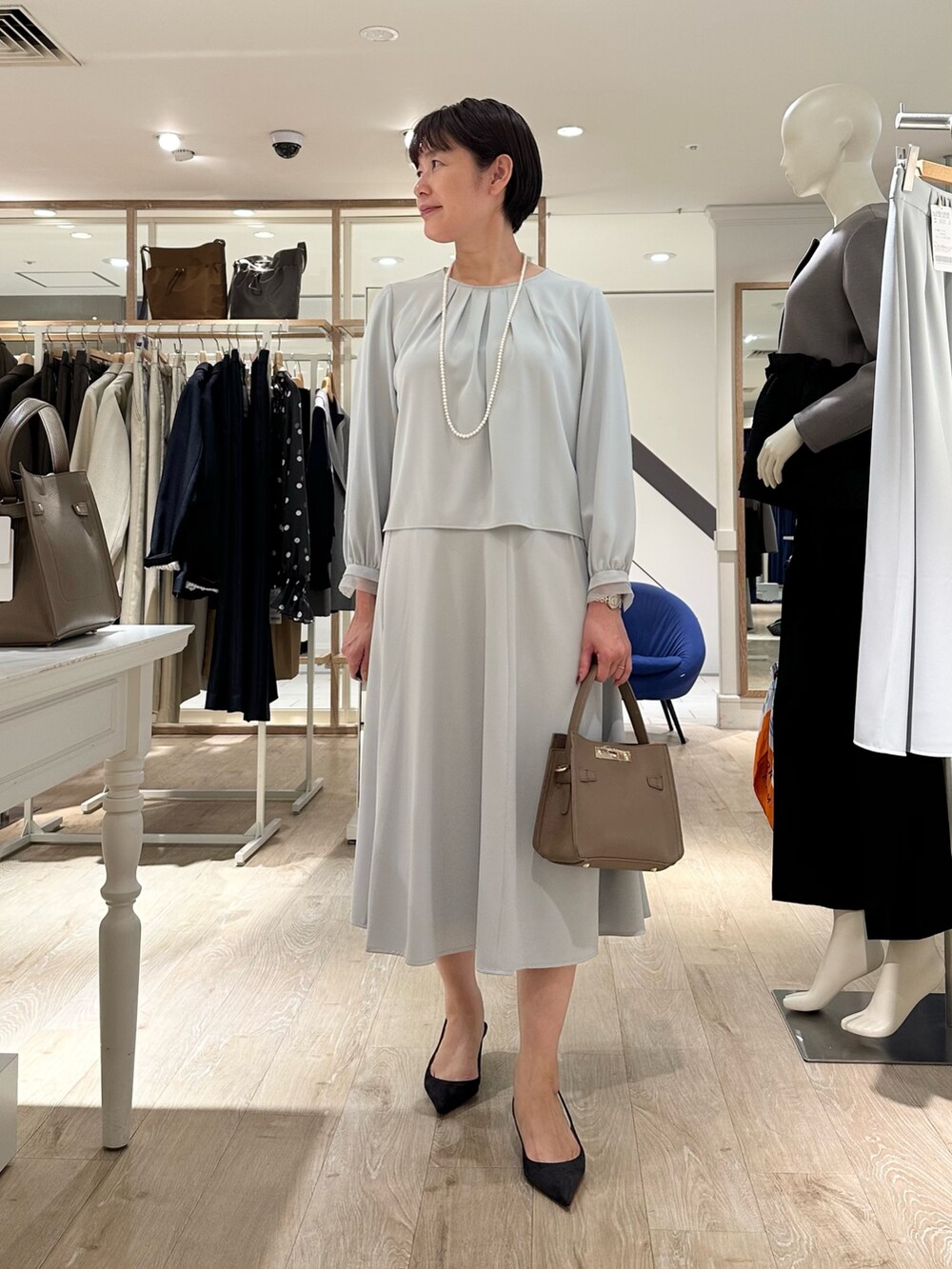 ベージュ系のショルダーバッグ、ブルー系のスカート、ブルー系のシャツ/ブラウスを着用したレディースの秋コーディネートの7枚目の写真