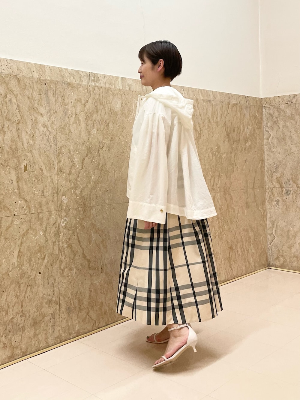 ホワイト系のサンダル、ベージュ系のスカート、ホワイト系のマウンテンパーカーを着用したレディースの春コーディネートの2枚目の写真