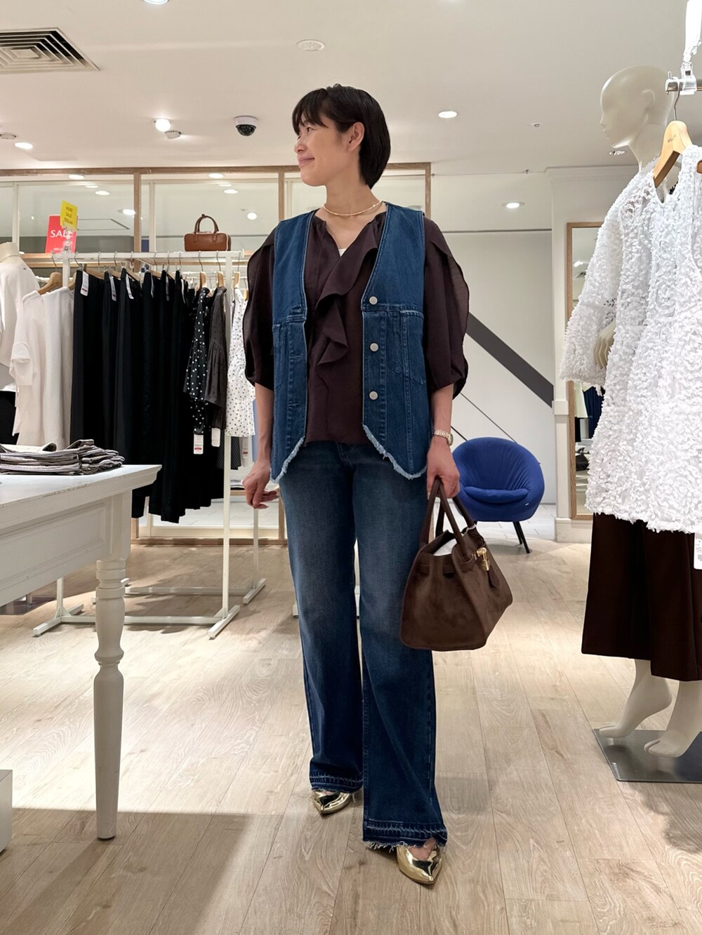 ブラウン系のシャツ/ブラウス、ブルー系のベスト、ブラウン系のトートバッグを着用したレディースの夏コーディネートの4枚目の写真