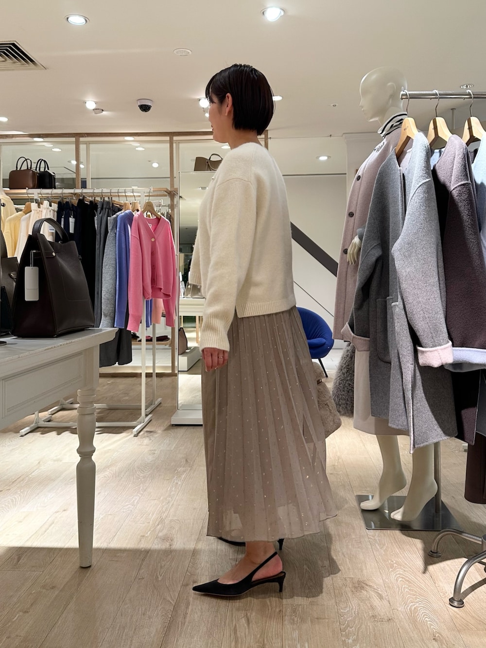 ホワイト系のニット/セーター、ブラウン系のスカート、ベージュ系のトートバッグを着用したレディースの秋コーディネートの2枚目の写真