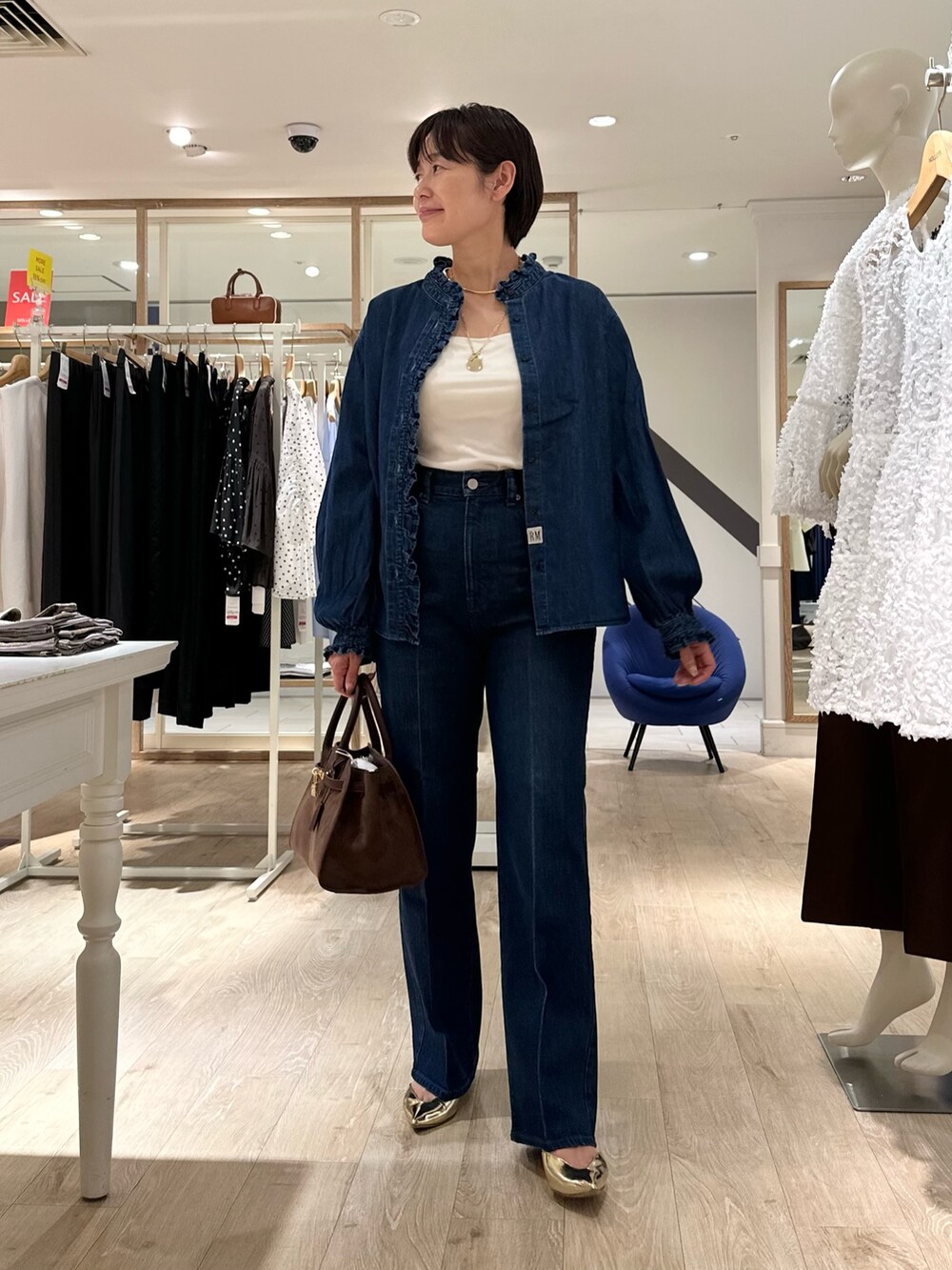 ブラウン系のトートバッグ、ブルー系のデニムパンツ、ブルー系のシャツ/ブラウスを着用したレディースの夏コーディネートの3枚目の写真