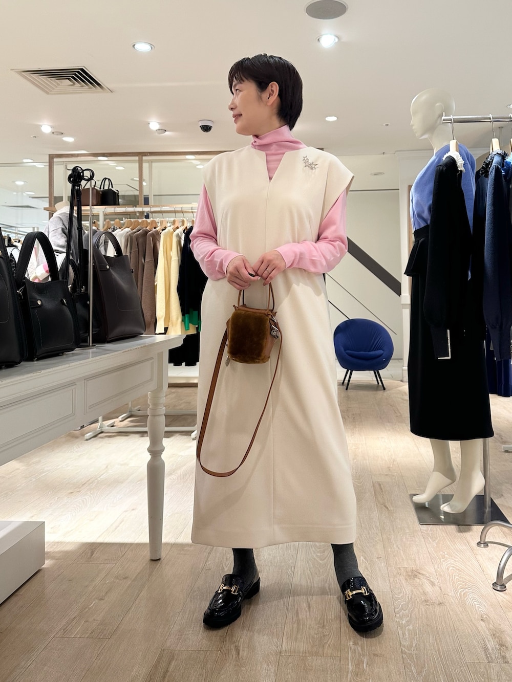 ブラック系のローファー、イエロー系のショルダーバッグ、ホワイト系のワンピースを着用したレディースの冬コーディネートの5枚目の写真