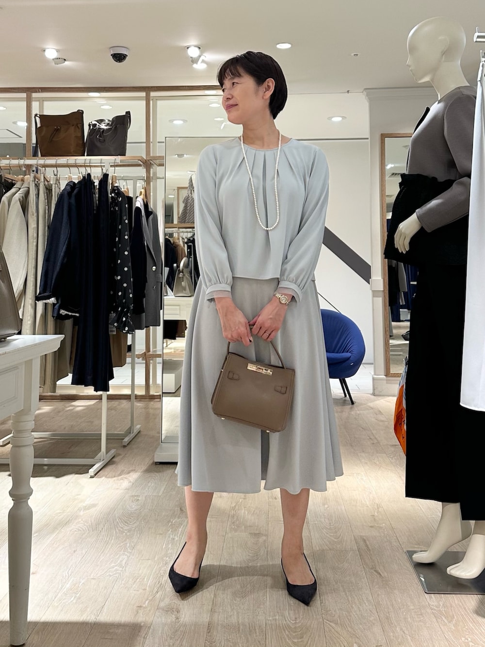 ベージュ系のショルダーバッグ、ブルー系のスカート、ブルー系のシャツ/ブラウスを着用したレディースの秋コーディネートの5枚目の写真