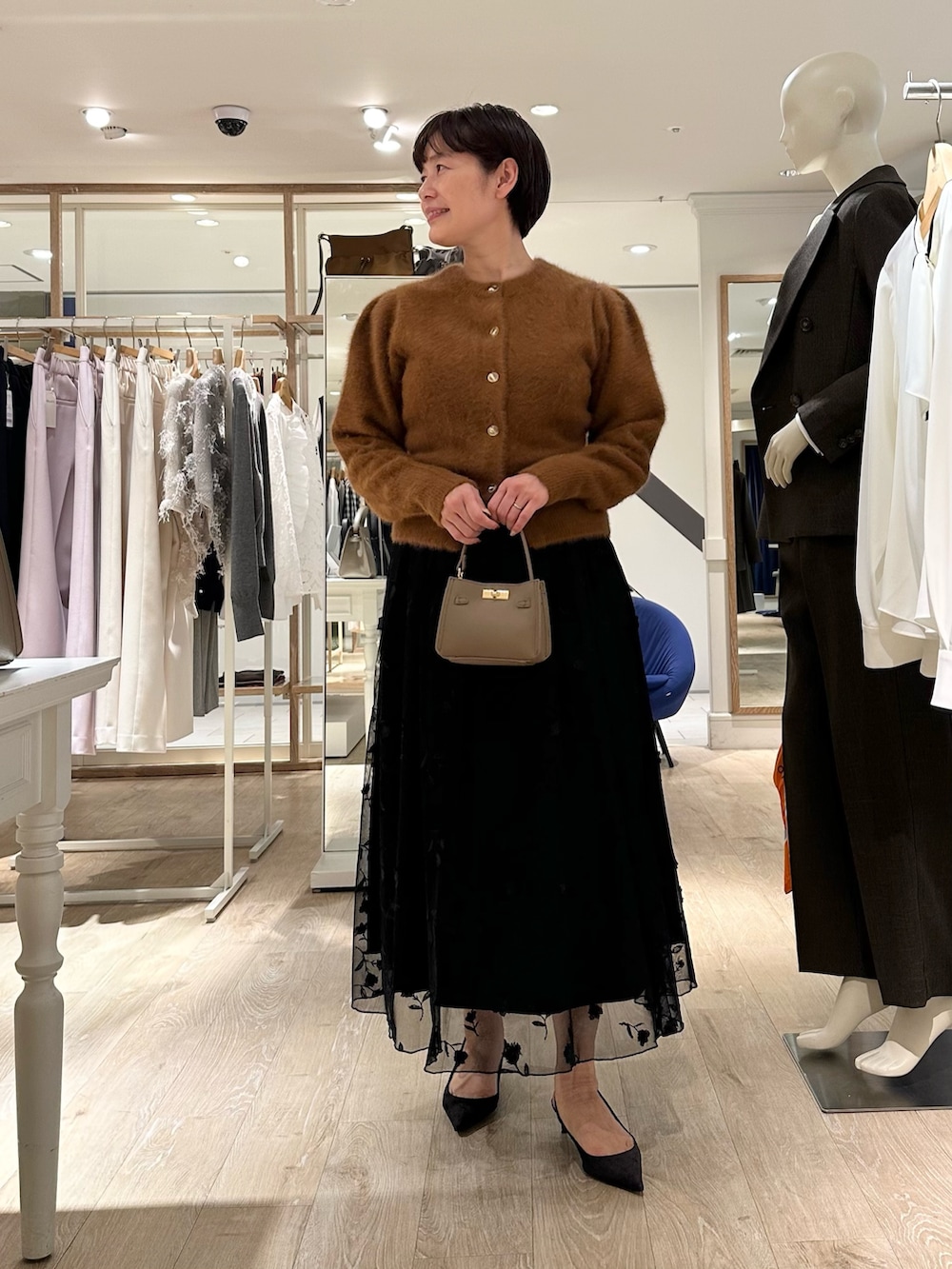ブラウン系のカーディガン/ボレロ、ブラック系のスカート、ベージュ系のショルダーバッグを着用したレディースの秋コーディネートの2枚目の写真