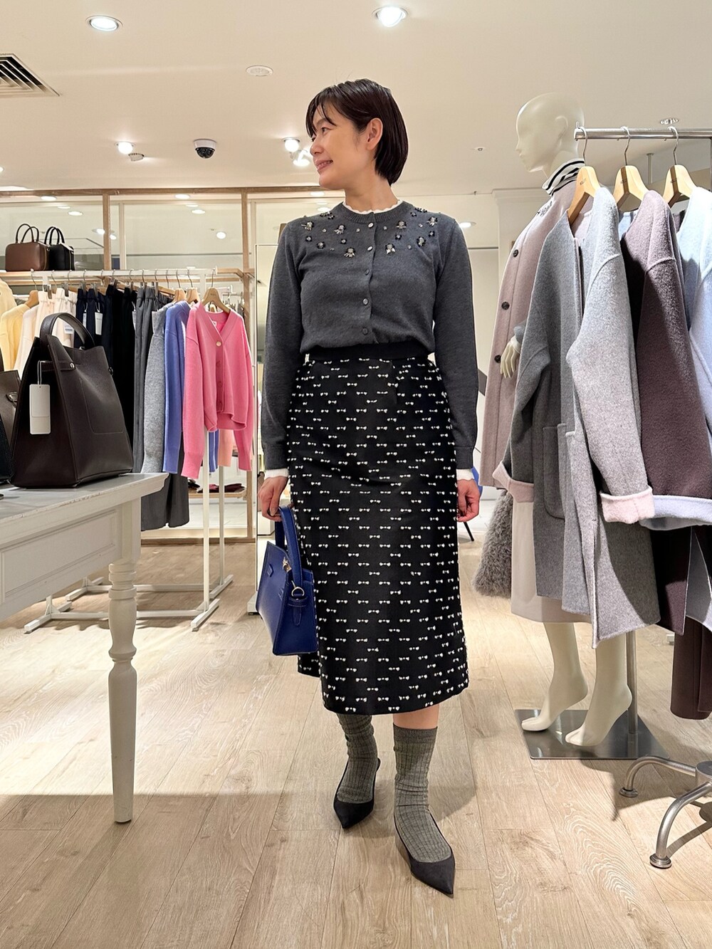 グレー系のカーディガン/ボレロ、ブラック系のスカート、ブルー系のショルダーバッグを着用したレディースの冬コーディネートの5枚目の写真