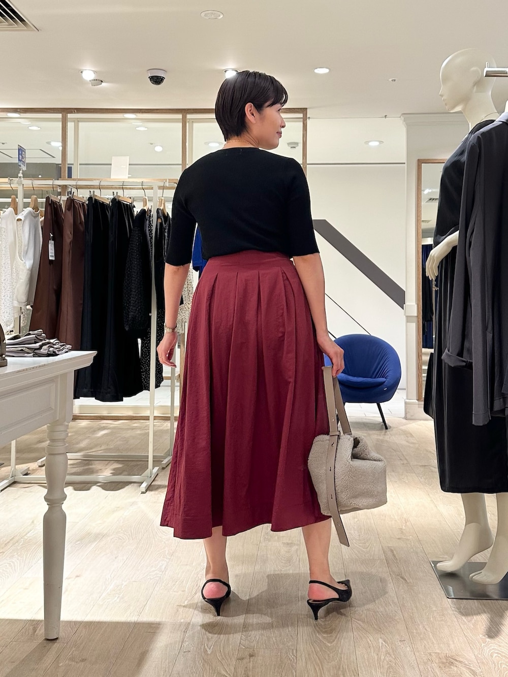 レッド系のスカート、ベージュ系のショルダーバッグ、ブラック系のニット/セーターを着用したレディースの秋コーディネートの8枚目の写真