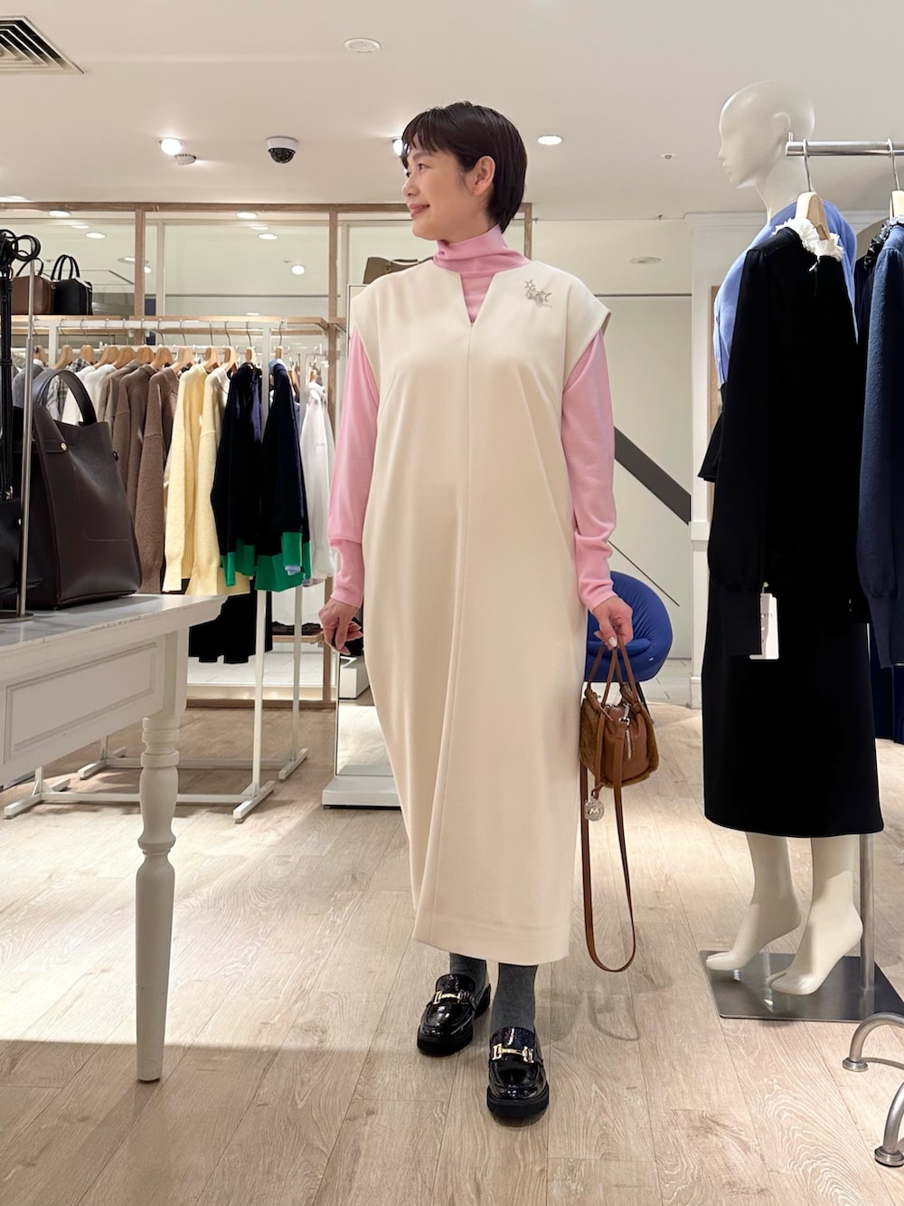 ブラック系のローファー、イエロー系のショルダーバッグ、ホワイト系のワンピースを着用したレディースの冬コーディネートの6枚目の写真