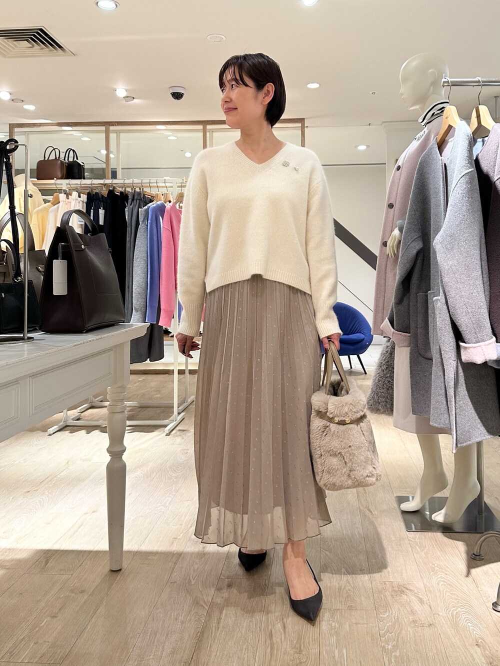 ホワイト系のニット/セーター、ブラウン系のスカート、ベージュ系のトートバッグを着用したレディースの秋コーディネートの7枚目の写真