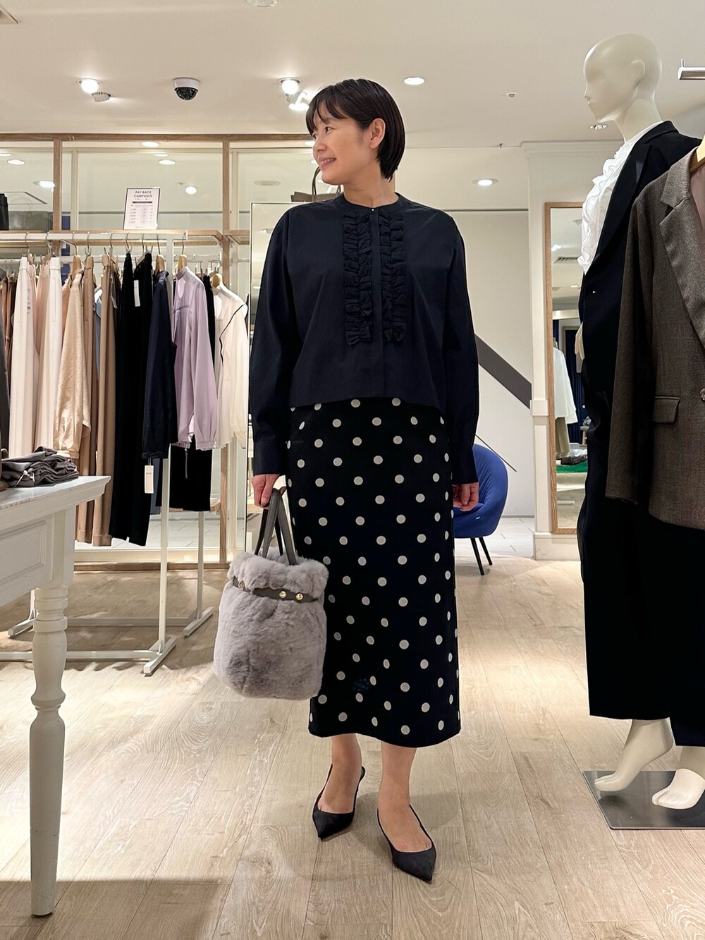 ベージュ系のトートバッグ、ブラック系のスカート、ブルー系のシャツ/ブラウスを着用したレディースの秋コーディネートの5枚目の写真