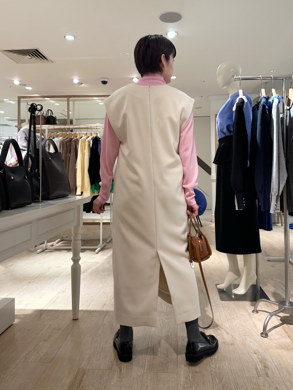 ブラック系のローファー、イエロー系のショルダーバッグ、ホワイト系のワンピースを着用したレディースの冬コーディネートの3枚目の写真