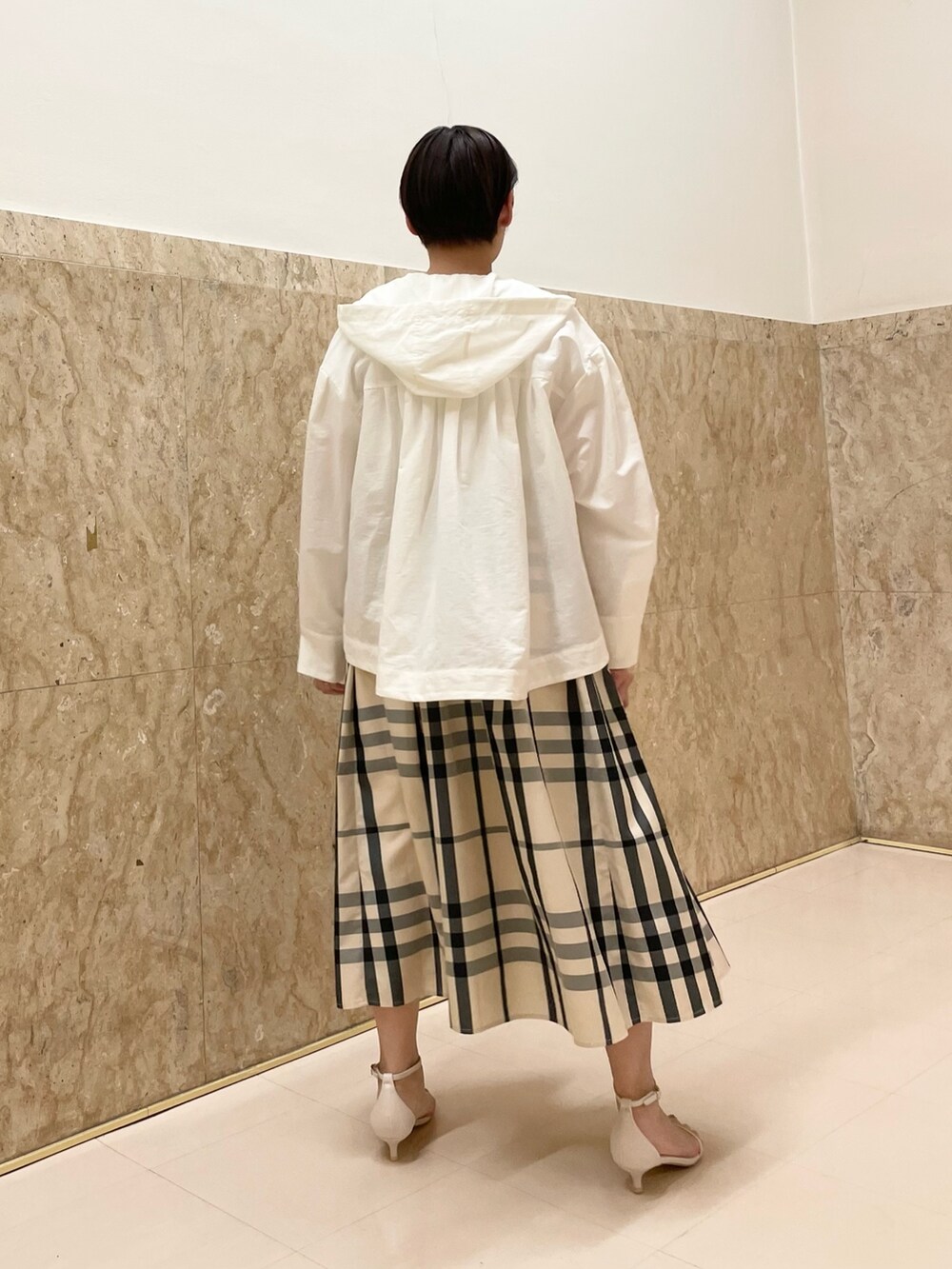 ホワイト系のサンダル、ベージュ系のスカート、ホワイト系のマウンテンパーカーを着用したレディースの春コーディネートの7枚目の写真