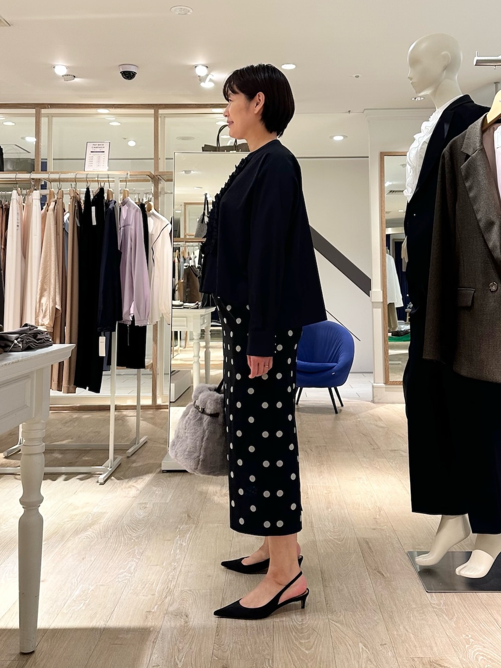 ベージュ系のトートバッグ、ブラック系のスカート、ブルー系のシャツ/ブラウスを着用したレディースの秋コーディネートの2枚目の写真