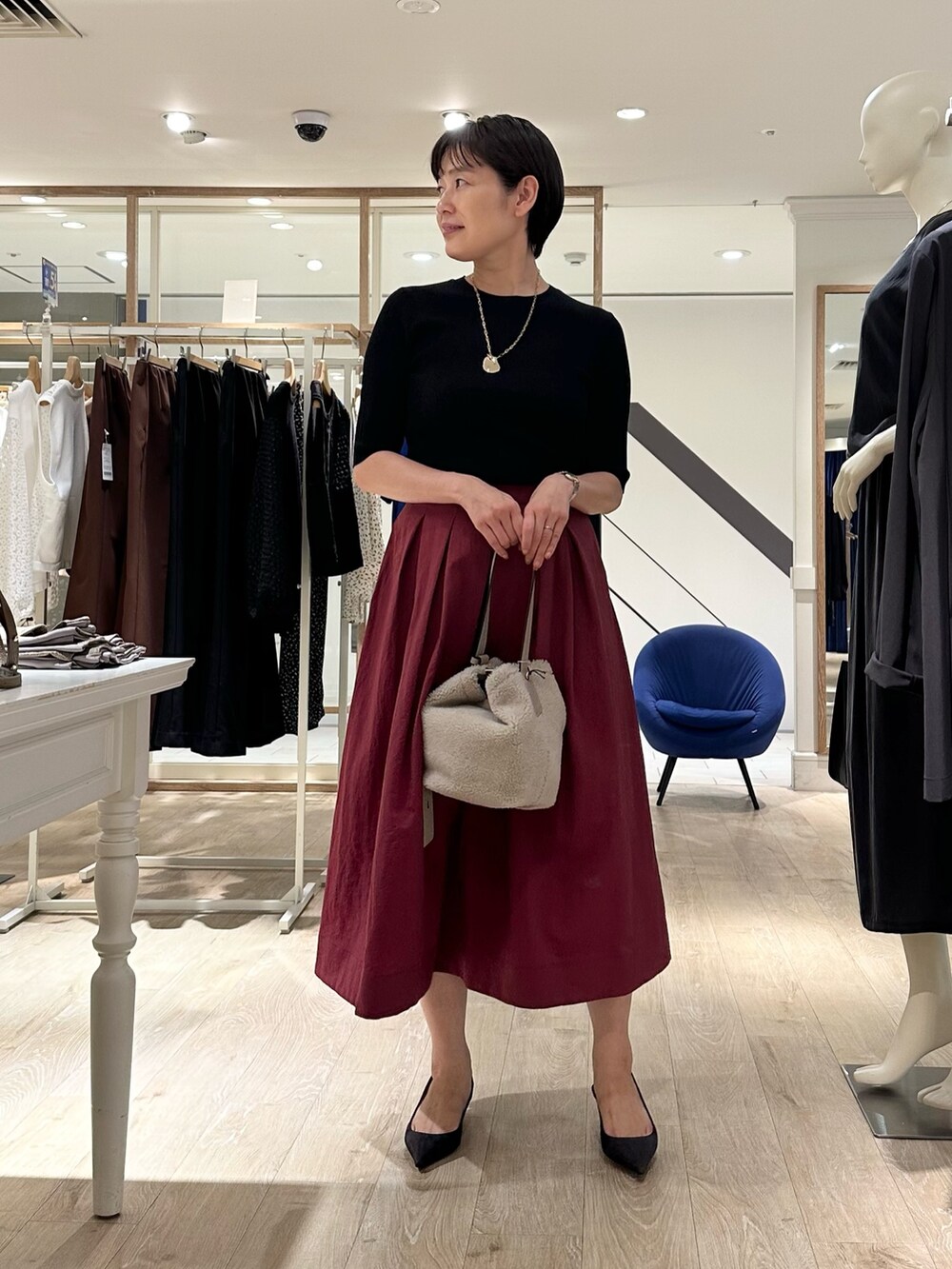 レッド系のスカート、ベージュ系のショルダーバッグ、ブラック系のニット/セーターを着用したレディースの秋コーディネートの10枚目の写真