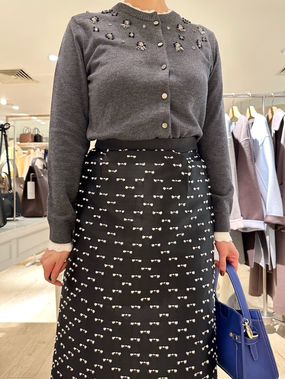 グレー系のカーディガン/ボレロ、ブラック系のスカート、ブルー系のショルダーバッグを着用したレディースの冬コーディネートの8枚目の写真