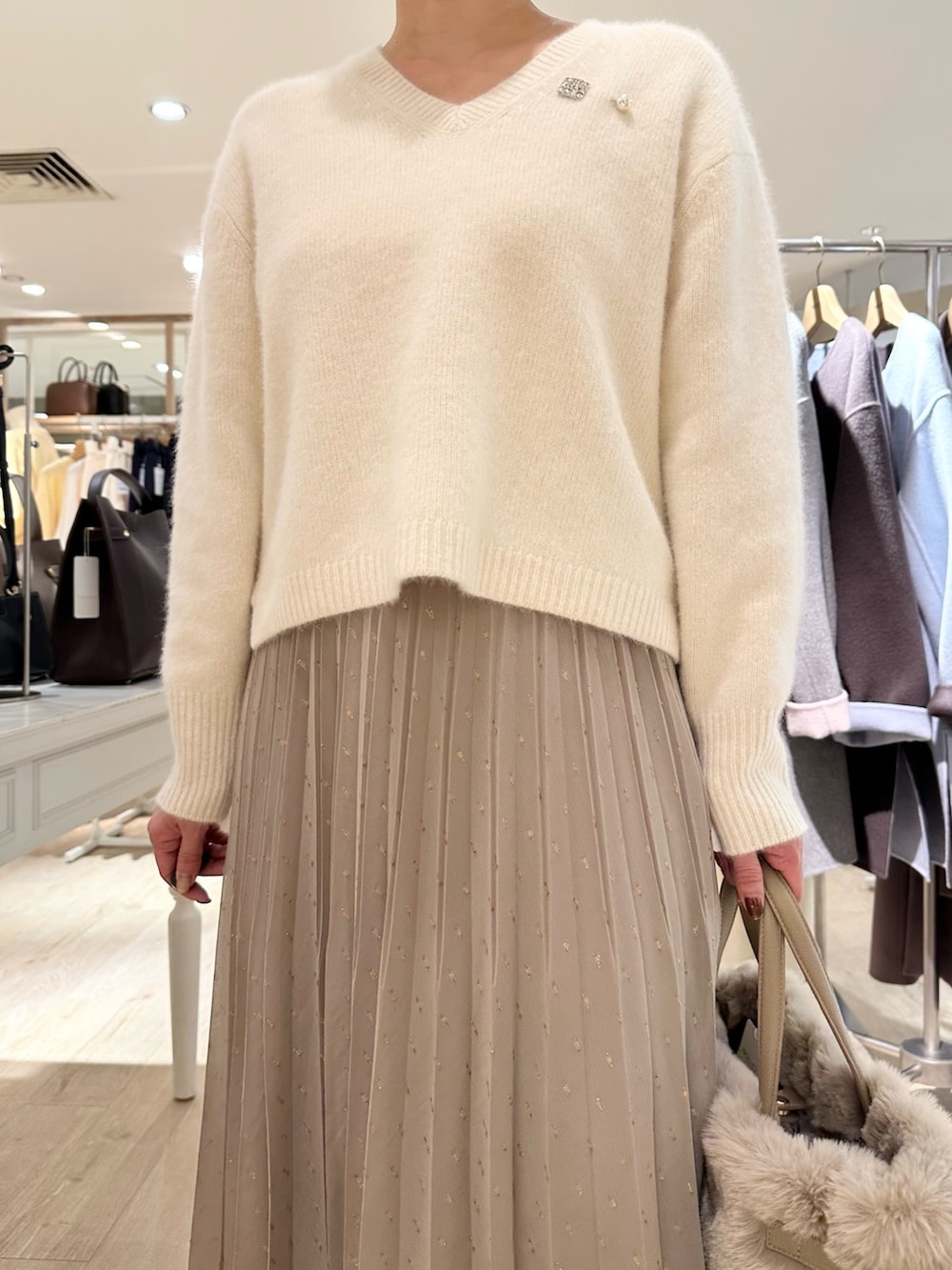 ホワイト系のニット/セーター、ブラウン系のスカート、ベージュ系のトートバッグを着用したレディースの秋コーディネートの6枚目の写真