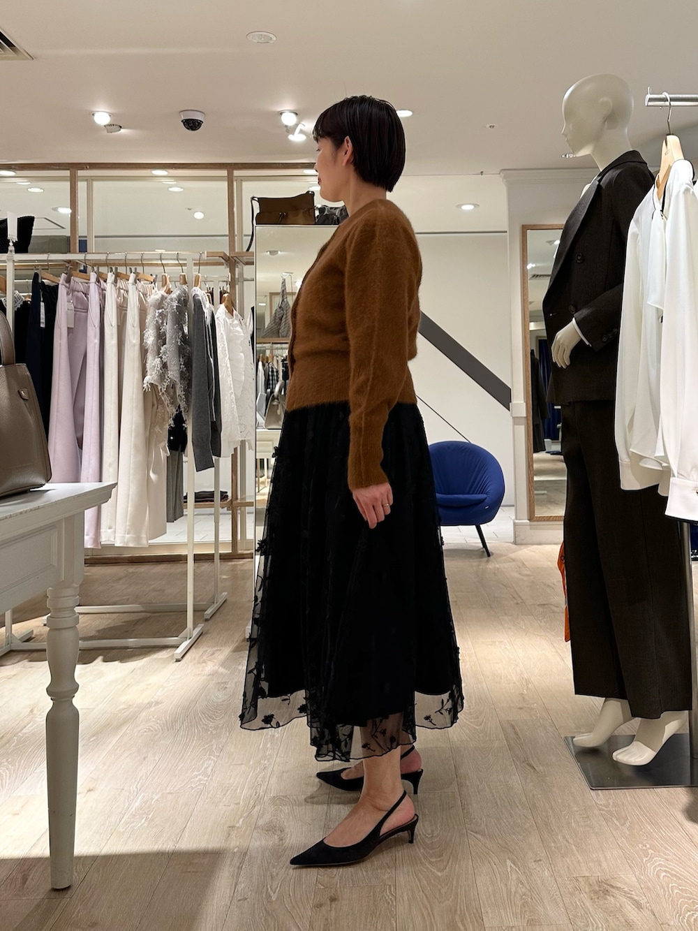 ブラウン系のカーディガン/ボレロ、ブラック系のスカート、ベージュ系のショルダーバッグを着用したレディースの秋コーディネートの3枚目の写真