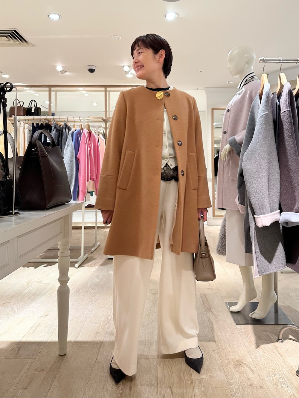 イエロー系のノーカラーコート、ホワイト系のカーディガン/ボレロ、ブラック系のシャツ/ブラウスを着用したレディースの冬コーディネートの6枚目の写真