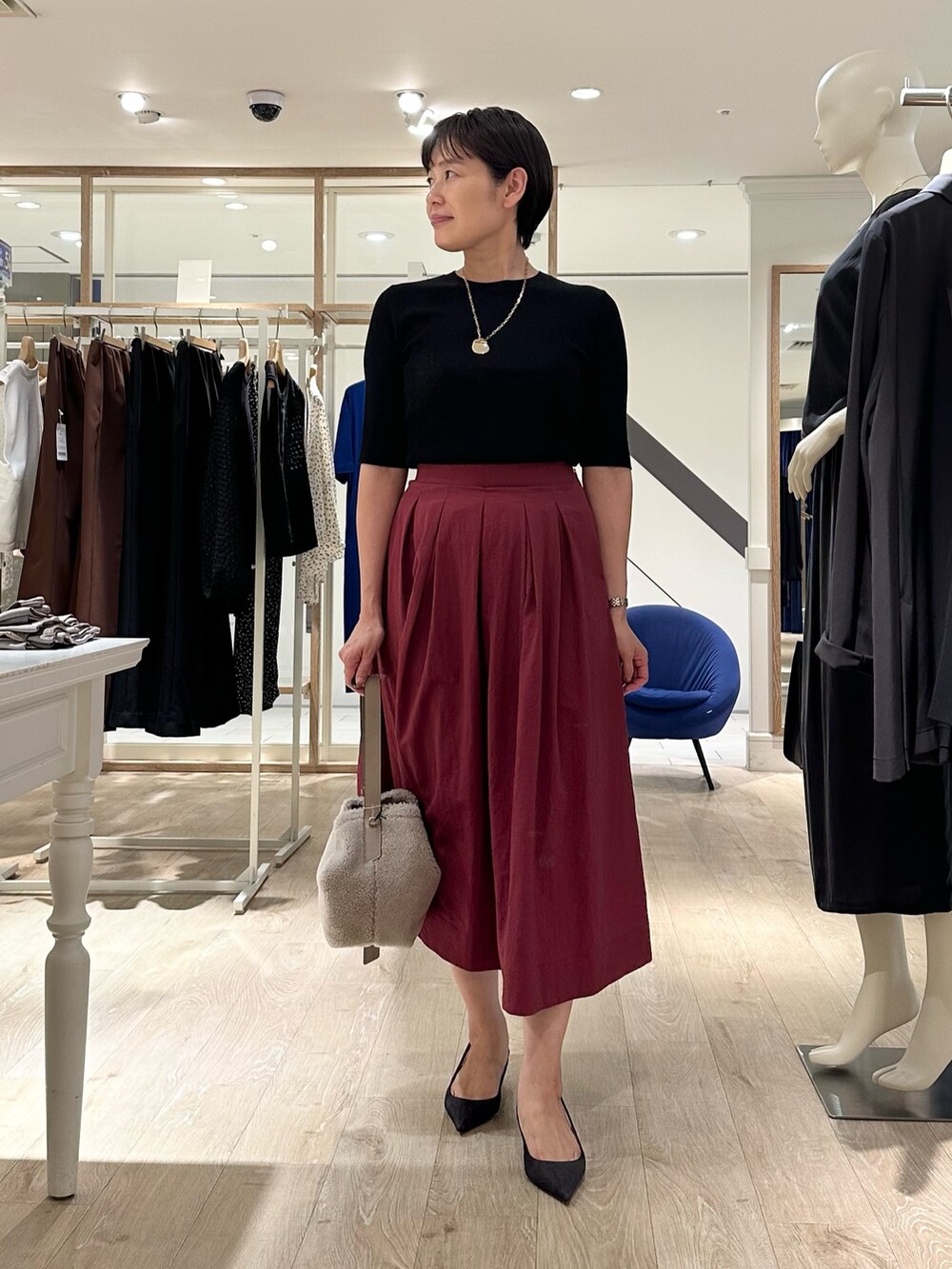 レッド系のスカート、ベージュ系のショルダーバッグ、ブラック系のニット/セーターを着用したレディースの秋コーディネートの9枚目の写真