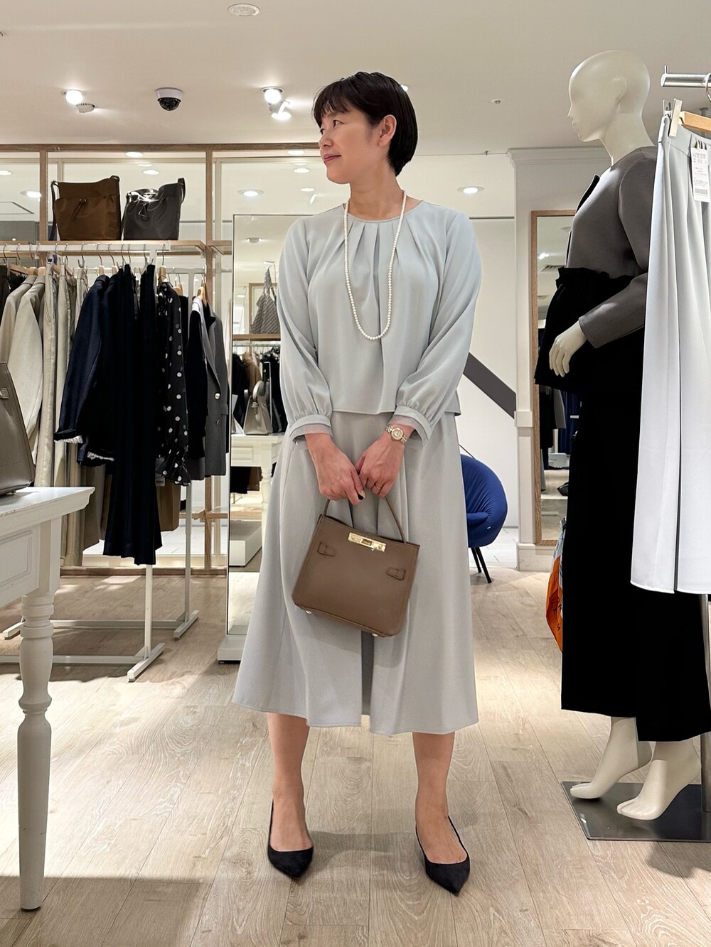 ベージュ系のショルダーバッグ、ブルー系のスカート、ブルー系のシャツ/ブラウスを着用したレディースの秋コーディネートの6枚目の写真