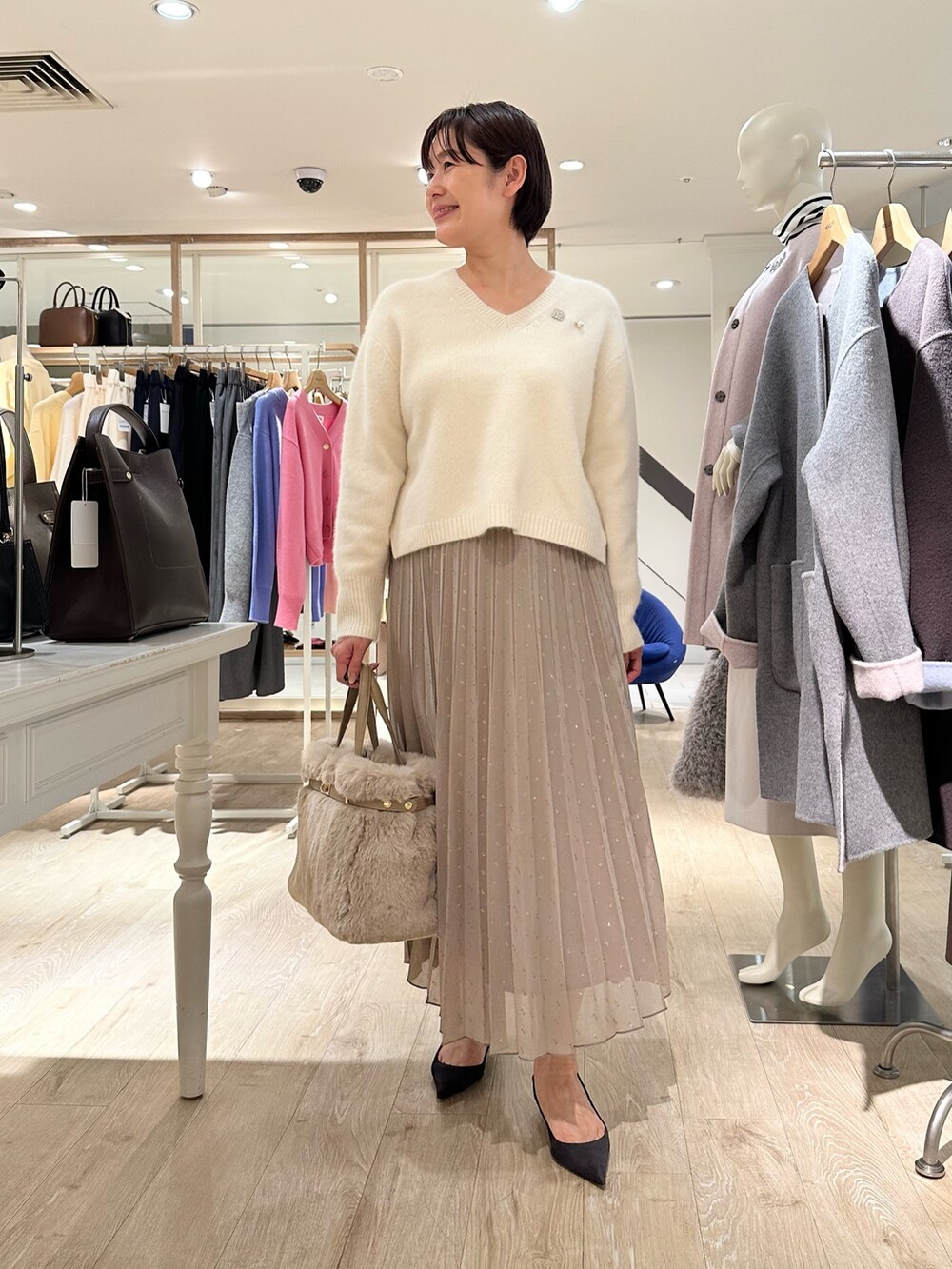 ホワイト系のニット/セーター、ブラウン系のスカート、ベージュ系のトートバッグを着用したレディースの秋コーディネートの8枚目の写真