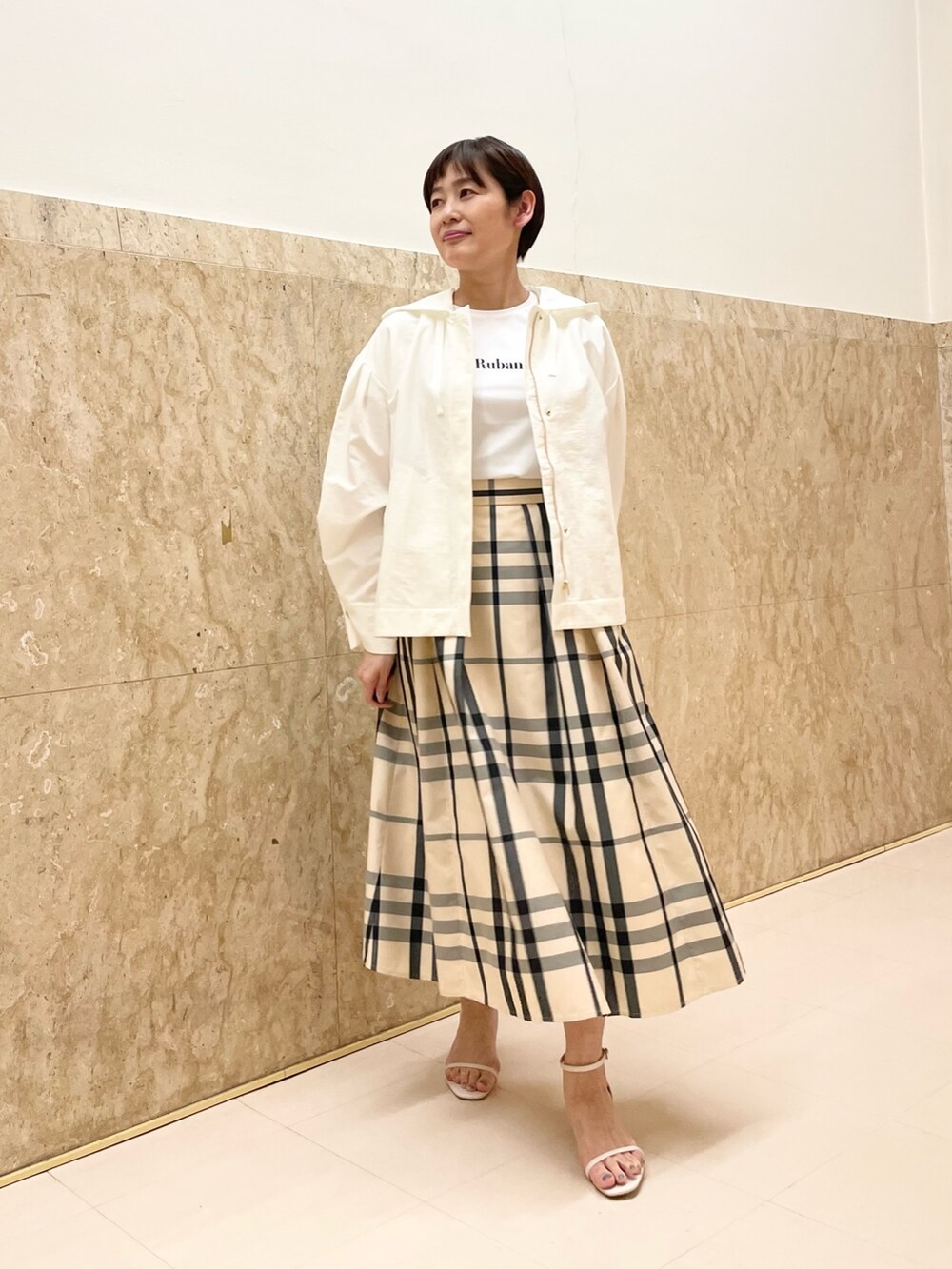 ホワイト系のサンダル、ベージュ系のスカート、ホワイト系のマウンテンパーカーを着用したレディースの春コーディネートの8枚目の写真