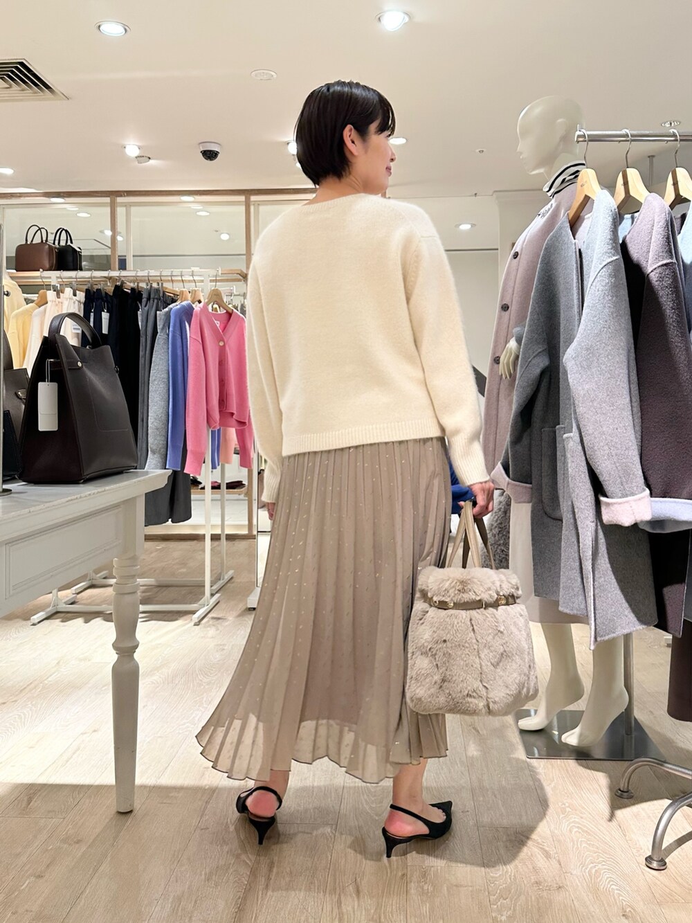 ホワイト系のニット/セーター、ブラウン系のスカート、ベージュ系のトートバッグを着用したレディースの秋コーディネートの3枚目の写真