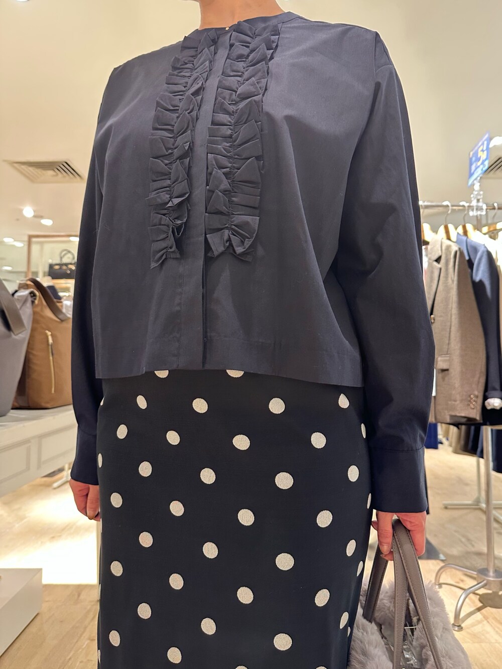 ベージュ系のトートバッグ、ブラック系のスカート、ブルー系のシャツ/ブラウスを着用したレディースの秋コーディネートの9枚目の写真