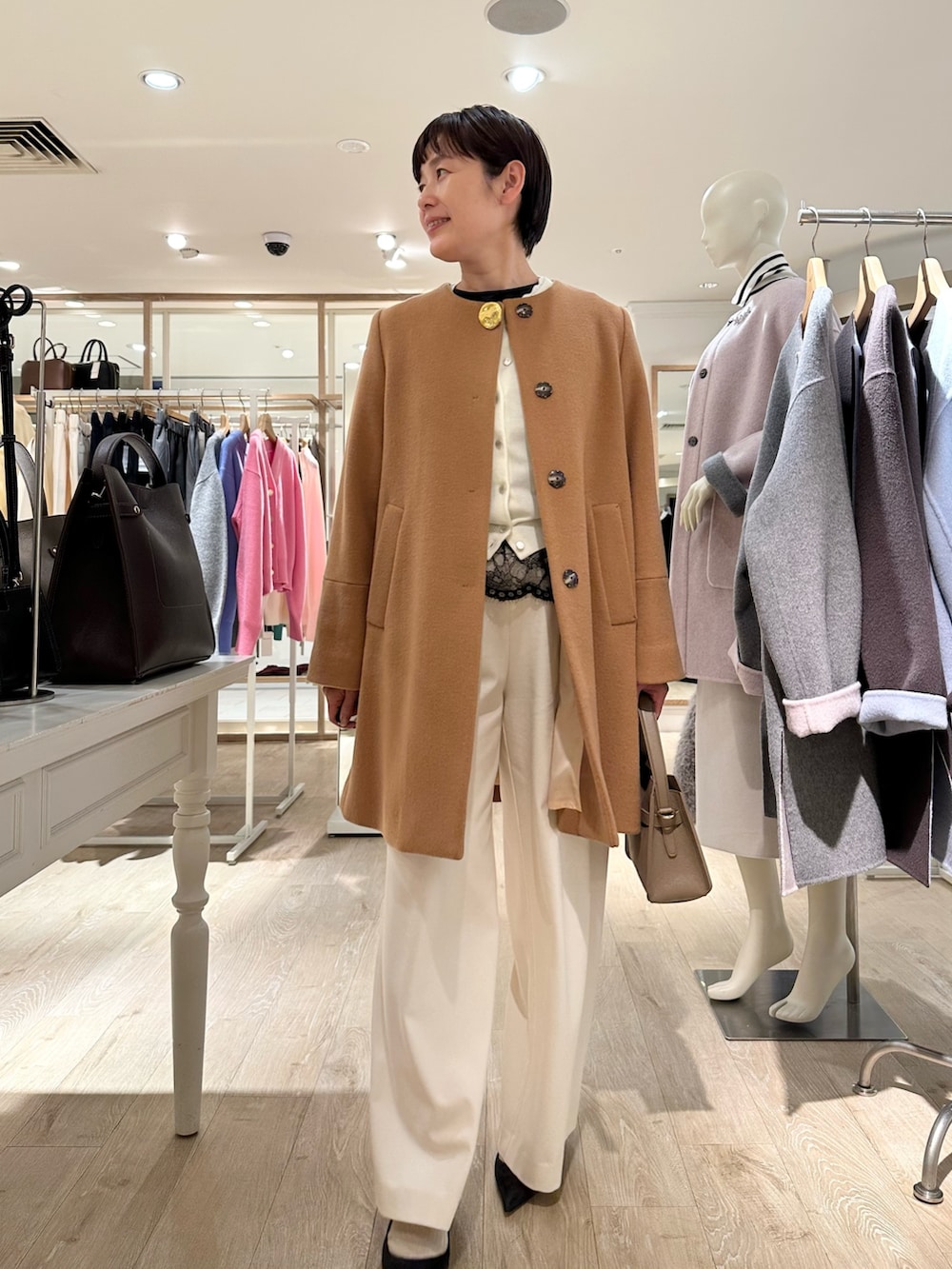 イエロー系のノーカラーコート、ホワイト系のカーディガン/ボレロ、ブラック系のシャツ/ブラウスを着用したレディースの冬コーディネートの4枚目の写真