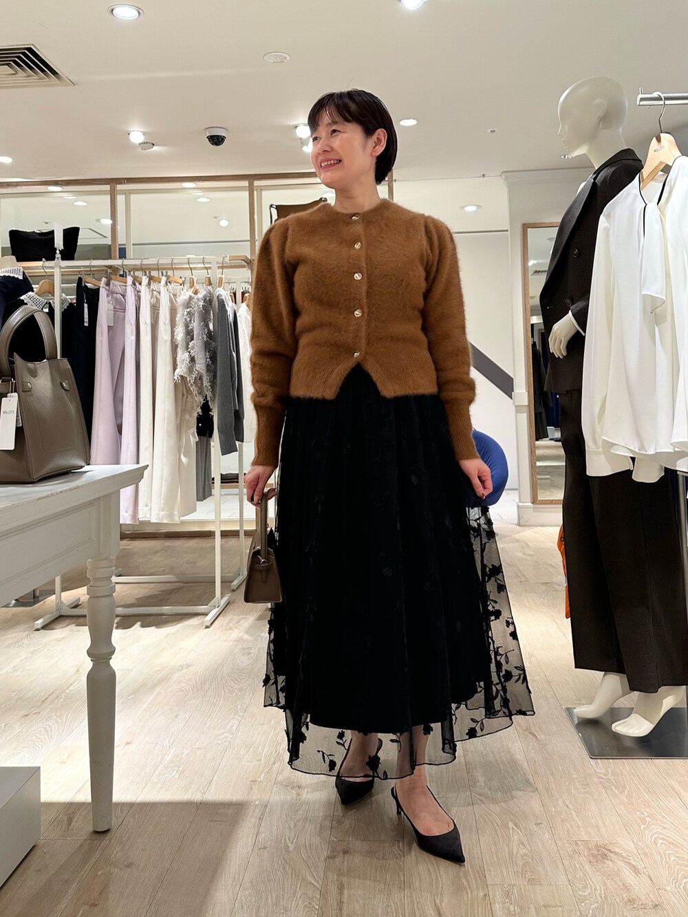 ブラウン系のカーディガン/ボレロ、ブラック系のスカート、ベージュ系のショルダーバッグを着用したレディースの秋コーディネートの5枚目の写真