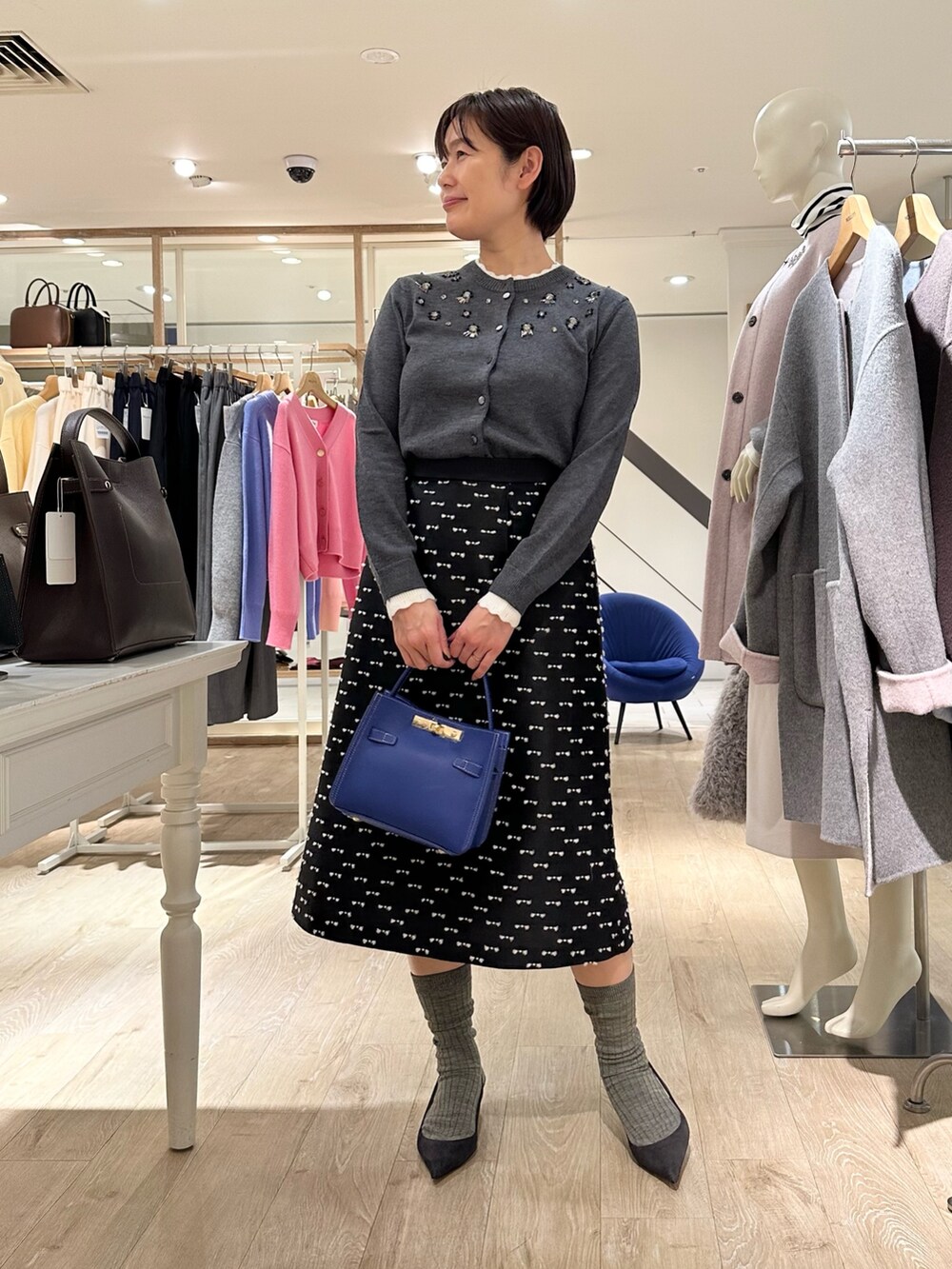 グレー系のカーディガン/ボレロ、ブラック系のスカート、ブルー系のショルダーバッグを着用したレディースの冬コーディネートの6枚目の写真